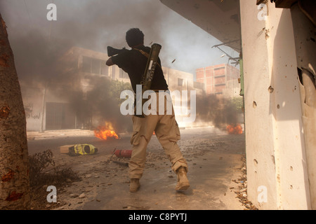 Rebel fighter battaglie cecchini nella piazza occupata dalle forze di Gheddafi sul finale il giorno della liberazione di Zarwiya Foto Stock