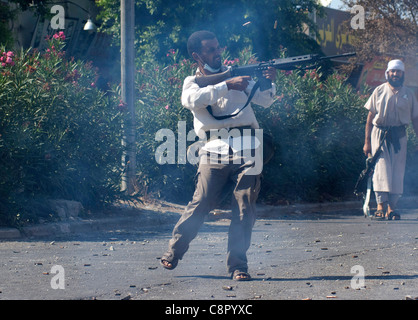 Rebel fighter battaglie cecchini nella piazza occupata dalle forze di Gheddafi sul finale il giorno della liberazione di Zarwiya Foto Stock