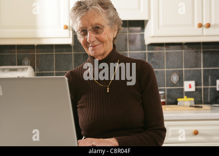 Donna anziana seduta al suo computer portatile. Foto Stock