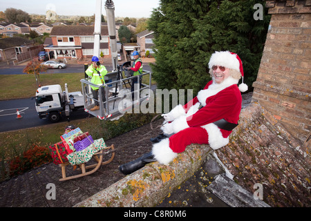 Santa Claus fornisce il suo roof top magic con l aiuto di un cherry picker REGNO UNITO Foto Stock