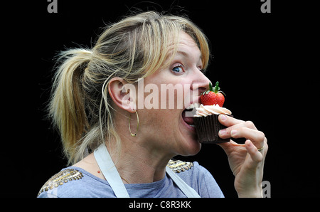 Celebrity Chef e il libro di ricette autore Rachel Allen foto di mangiare una tortina contro uno sfondo nero. Foto Stock