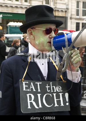 Un manifestante con un "mangiare il ricco!" segno ad un anti-capitalista protestare Foto Stock