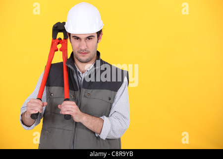 Ritratto di artigiano tenendo la chiave contro sfondo giallo Foto Stock