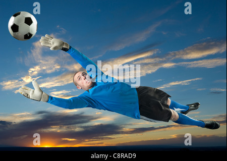 Caucasian soccer goalie jumping a mezz aria cattura la sfera Foto Stock