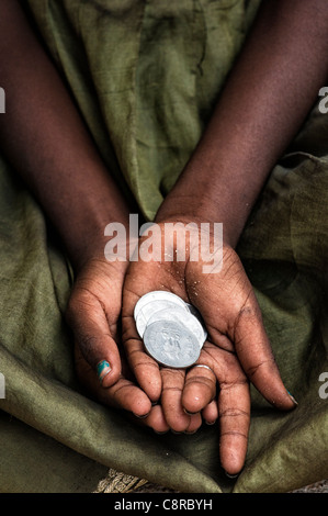 Indiano ragazza di strada mendicando per soldi con il rupee monete in mano. Foto Stock