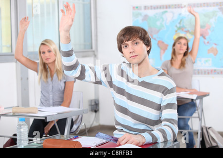 Gli studenti ad alzare la mano in classe Foto Stock