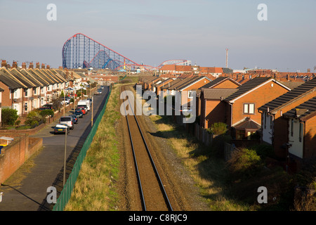 Linea ferroviaria e righe di case offuscati da "Big One' roller coaster in Blackpool Pleasure Beach Foto Stock