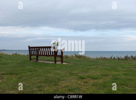 Memorial banco con fiori che si affaccia a sud Bay beach a Bridlington, nello Yorkshire, Regno Unito Foto Stock