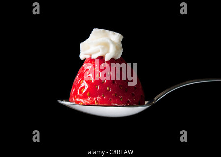 Fragole con panna sul cucchiaio Foto Stock