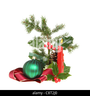 Natale Decorazioni per la tavola di fogliame stagionale, candela che brucia,ribbon e ninnolo isolata contro bianco Foto Stock