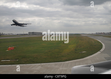 Un aereo di linea che decoltra all'aeroporto di Heathrow, Londra - vista dall'interno di un altro aereo. Foto Stock