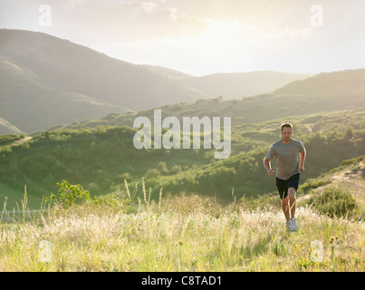 Uomo caucasico in esecuzione sulla collina in remoto Foto Stock