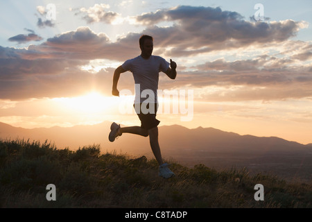 Uomo caucasico in esecuzione sulla collina in remoto Foto Stock