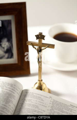 Aprire la bibbia con crocifisso, photo frame e il tè nero in background Foto Stock