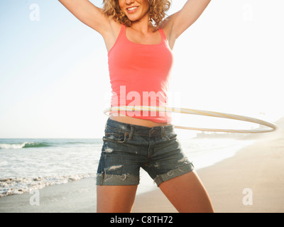 Stati Uniti, California, Malibu, giovane donna attraente esercitando con hoola hoop Foto Stock