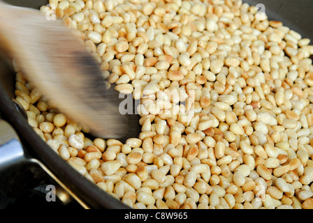 Dado di pino essendo chicchi tostati per migliorare il loro sapore prima di essere utilizzato. Foto Stock