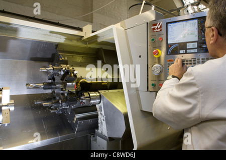 Programmi di ingegnere di dati su un tornio CNC macchina caricata con strumenti prima della lavorazione Foto Stock