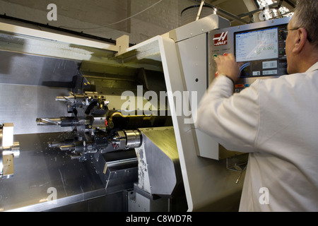 Programmi di ingegnere di dati su un tornio CNC macchina caricata con strumenti prima della lavorazione Foto Stock