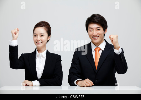 Asian imprenditore e imprenditrice seduto alla scrivania che mostra il pugno a mano Foto Stock
