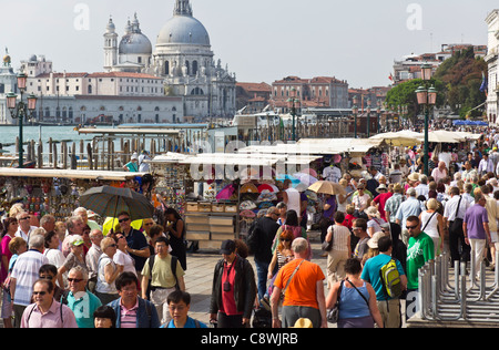 Venezia - affollata folla di turisti sulla Riva Schiavoni accanto al Canal Grande con sullo sfondo la chiesa della Salute. Foto Stock