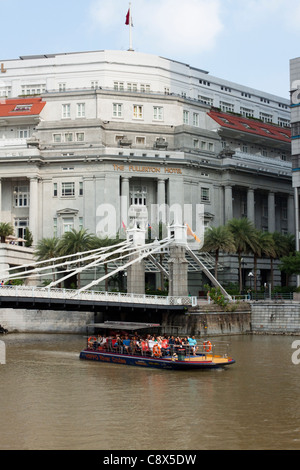 Il Fullerton Hotel e Cavenagh Bridge con la barca turistica, Singapore Foto Stock
