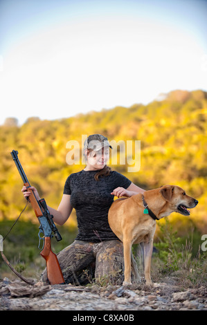 Donna attraente in camuffamento vestito con pistola e cane Foto Stock