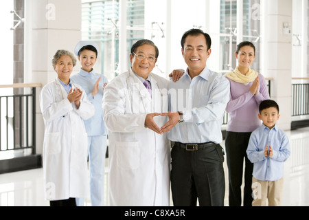 Padre fa a forma di cuore con le mani con i Senior medico Foto Stock