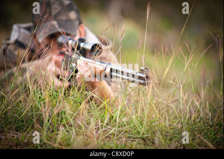 Mimetizzati hunter giacente in erba pistola di puntamento al bersaglio di caccia Foto Stock