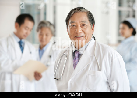 Senior medico con medici e infermiere in background Foto Stock