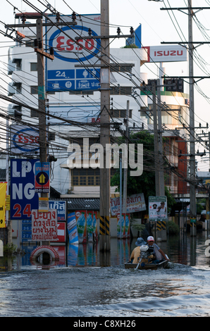 Gli uomini Thai drive passato barca allagata stazione ESSO in Rangsit, un sobborgo a nord di Bangkok, Tailandia. Mercoledì, 2 novembre 2011. Thailandia sta vivendo la sua peggiore inondazione in più di cinquant'anni. Credito: Kraig Lieb Foto Stock