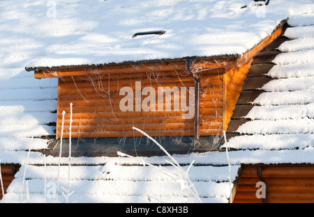 Vista sulla casa in legno il tetto coperto di neve Foto Stock