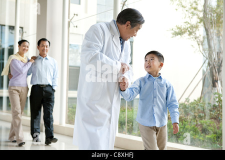 Giovane famiglia passeggiate in un corridoio di ospedale con un medico Foto Stock