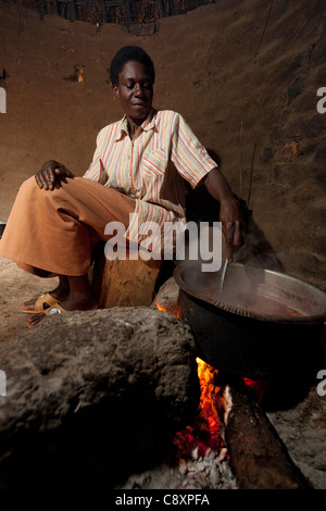Una donna cuochi una pentola di fagioli su un fuoco aperto nel villaggio Katirio, Kibuku distretto, Uganda. Foto Stock