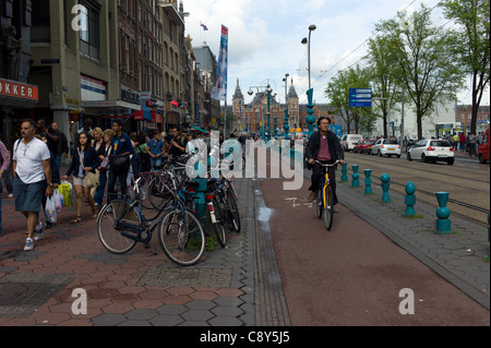 Amsterdam occupato con le persone e i ciclisti con il Centraal stazione ferroviaria in background Foto Stock