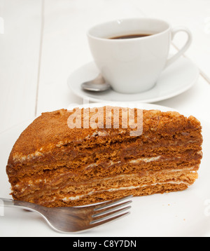 La tradizionale produzione di miele la torta su piastra bianca e la tazza di caffè sul tavolo Foto Stock