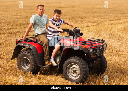 Un giovane ragazzo ha una corsa su di una moto quad con un adulto sul retro su una farm Regno Unito Foto Stock