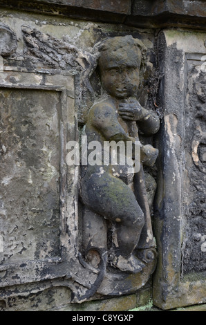 Un piuttosto alterate e indossato cherubino tenendo un avvisatore acustico su un secolo XVII tomba in Greyfriars Kirkyard, Edimburgo, Scozia. Foto Stock