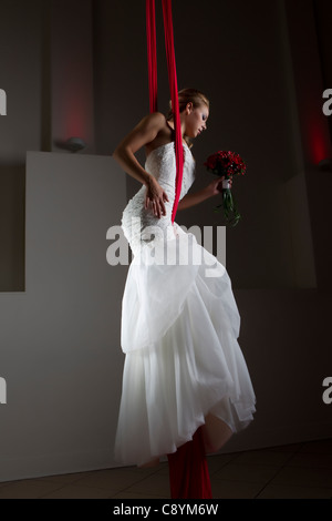 Modello femminile sete aeree acrobat in posa di un abito da sposa in aria Foto Stock