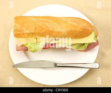 Un prosciutto e formaggio insalata baguette su una piastra con un coltello da sopra Foto Stock