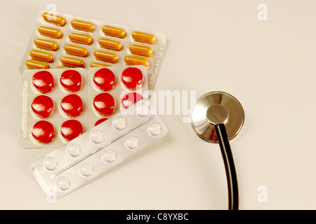 Pillole colorate e uno stetoscopio su un tavolo Foto Stock