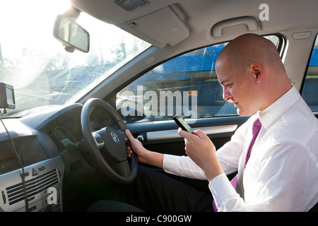 Uomo che utilizza il telefono cellulare durante la guida di auto in autostrada Foto Stock