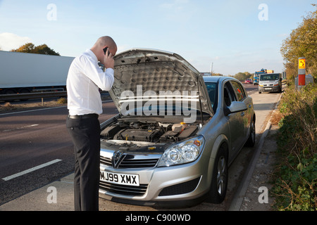 Uomo con ripartiti in auto lungo l'autostrada Foto Stock