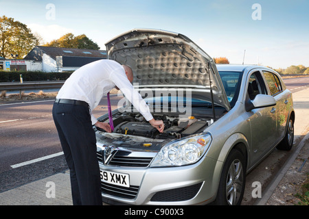 Uomo con ripartiti in auto lungo l'autostrada Foto Stock