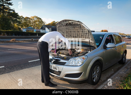 Uomo con ripartiti in auto lungo l'autostrada Foto Stock