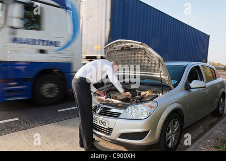 Uomo con ripartiti in auto lungo l'autostrada Foto Stock