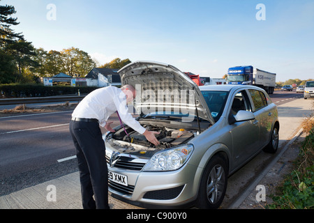 Uomo con ripartiti in auto lungo l'autostrada Foto Stock