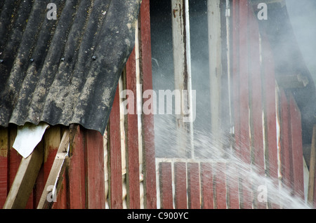 Spegnimento di un incendio di piccole dimensioni in una capanna in legno Foto Stock