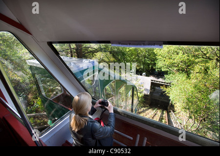 Un turista femminile scatta una fotografia da una delle vetture sull'acqua- equilibrato scogliera funicolare dalla stazione ferroviaria, uno dei la più ripida scogliera ferrovie in tutto il mondo presso il Centre for Alternative Technology in Galles del Nord Foto Stock