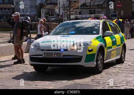 Ambulanza paramedico la guida accelerando lungo habourside a St. Ives, Cornwall, rispondendo alla chiamata di emergenza, con luci lampeggianti. Foto Stock