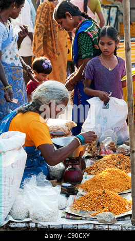 Il vecchio donna indiana indiana di vendita gli snack fritti in una strada del mercato di Puttaparthi. Andhra Pradesh, India Foto Stock